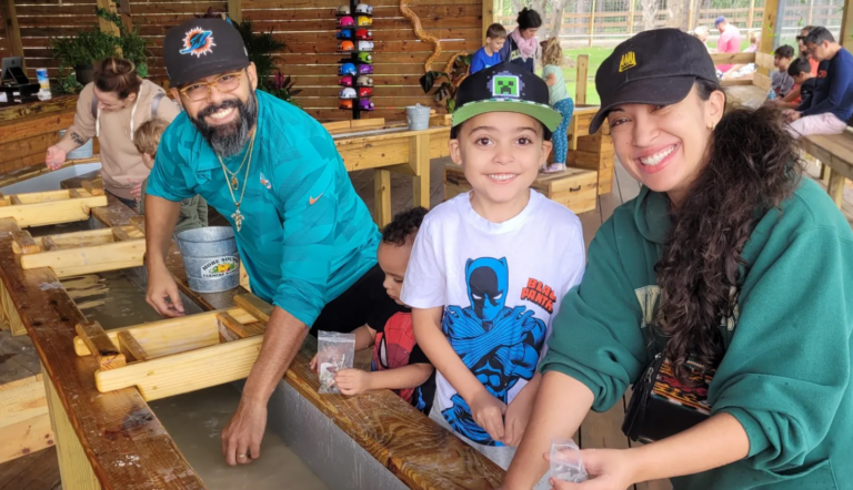 Families enjoy a fun-filled birthday party activity at an outdoor gem mining station, smiling and sifting through water channels for treasures. This hands-on experience is perfect for kids' parties, interactive events, and unique birthday celebrations that create unforgettable memories.