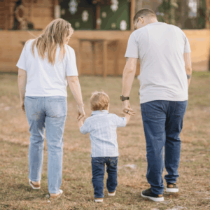 Parents and child walking hand in hand during a family photo session at Hobe Sound Farms.